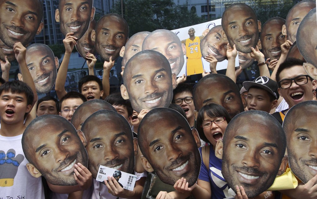 Fans hold posters of NBA basketball player Kobe Bryant as they wait for a promotional event in Guangzhou