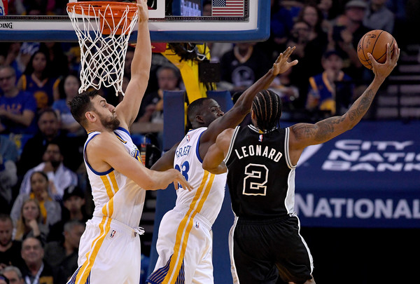 Kawhi Leonard attempts a shot against Draymond Green and Andrew Bogut